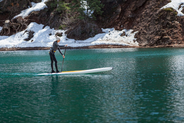 woman on a paddle board with snow in background