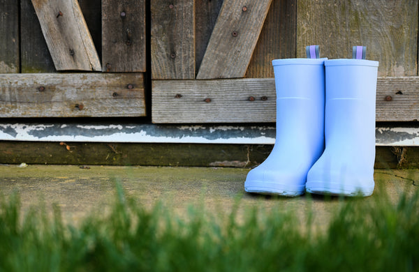 Kids Cirrus Charley Boots in Bonnie Blue in front of a barn with grass