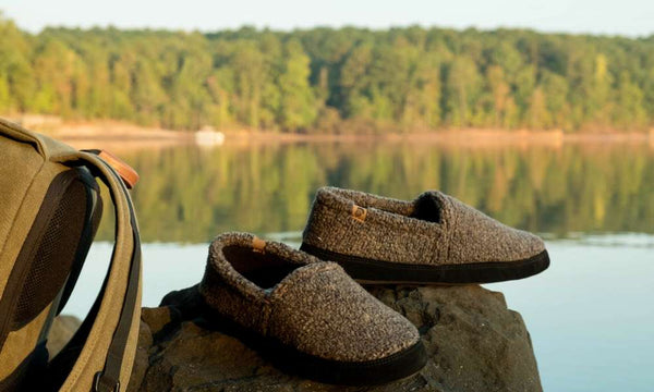 Men's Mocs in Earth Tex sitting on a rock next to a backpack overlooking a lake