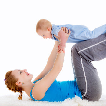 Mom lifting exercising with baby to tighten loose skin after pregnancy