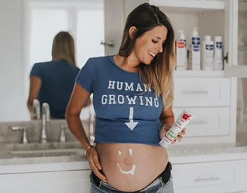 Woman applying stretch marks cream on pregnant belly