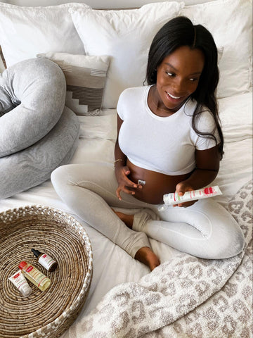 Woman applying lotion on pregnant belly after learning the pregnancy facts