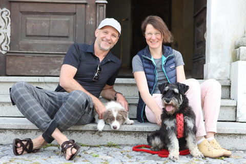 Dr. Peter Dobias and Dr. Eva Furnshuss sitting on steps with their two dogs