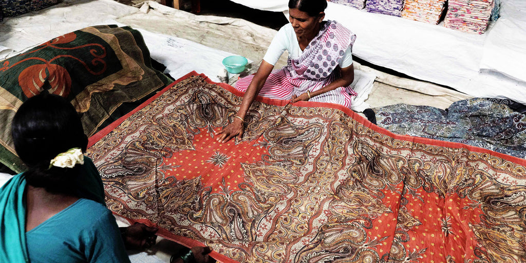 Artisanal women inspecting the final silk scarves and textiles for any major flaws