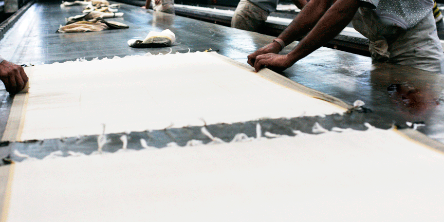 Artisans applying the fabric on hot wax tables for silkscreen printing process