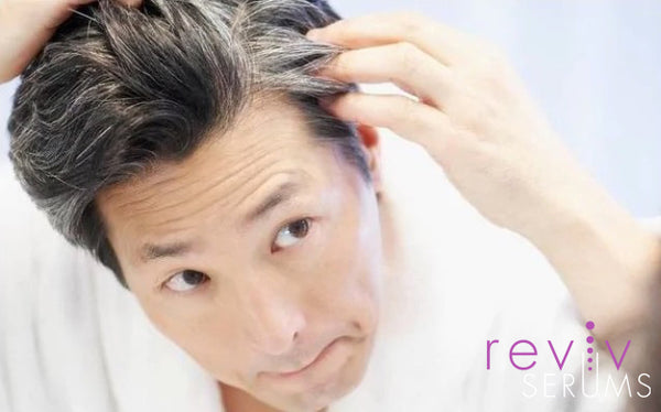 Asian man examining premature greying hair