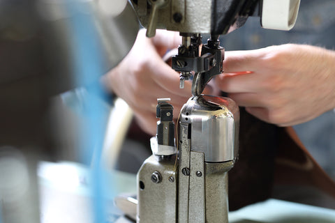 A worker sewing a shoe on a post-bed sewing machine