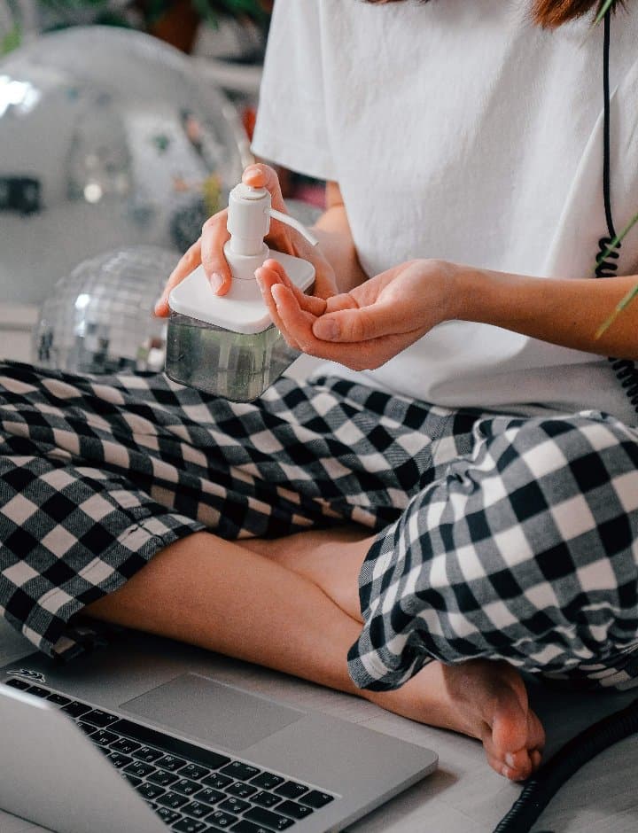 person in black and white checkered pants using a hand sanitizer