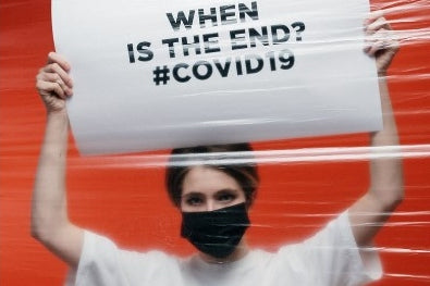 a woman holding a sign and wearing face mask