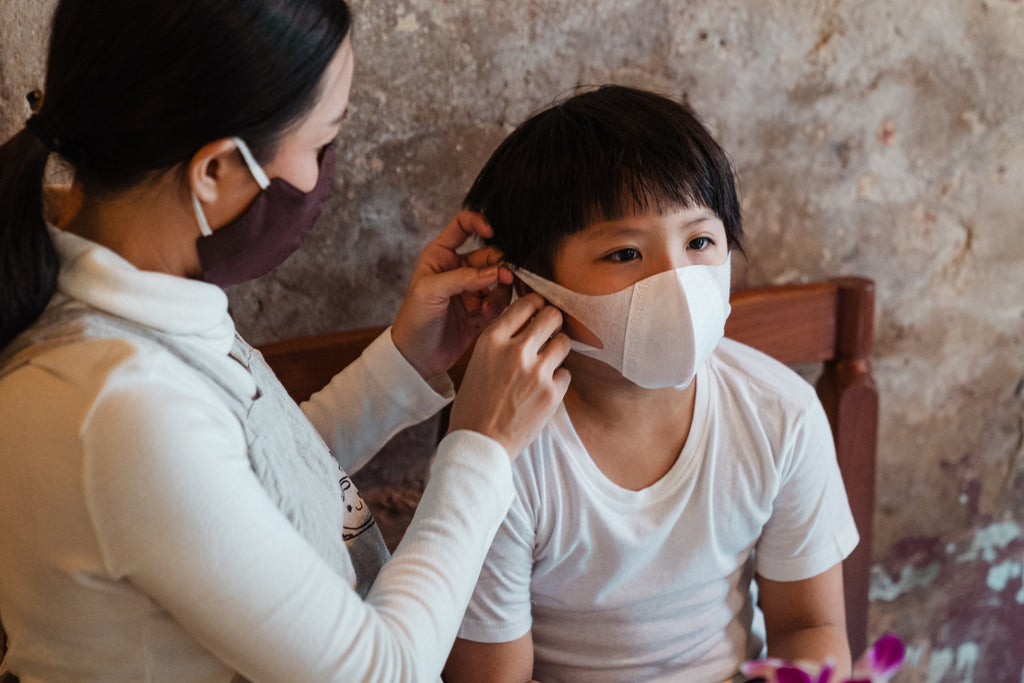 a woman putting mask on his son
