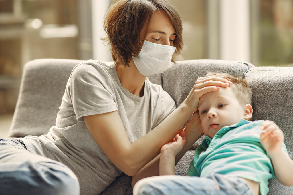 Woman wearing face mask holding her sick child