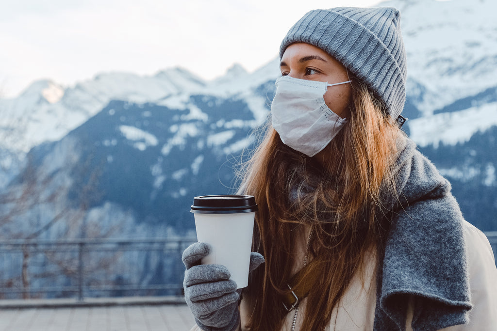 a woman in grey knit cap holding a disposable cup