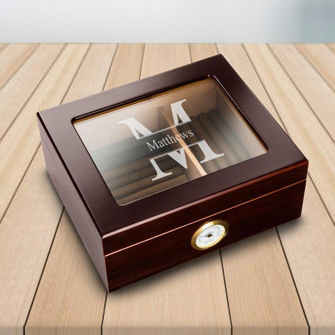 A Mahogany personalized humidor filled with cigars that has a glass top that says matthews