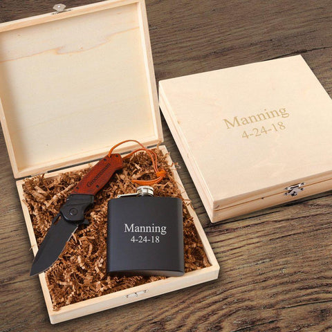 A wooden knife box with a personalized pocket knife and drinking flask inside