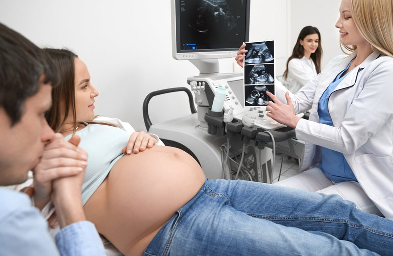 mulher gravida segurando a mão do parceiro durante uma sessão de ultrasom
