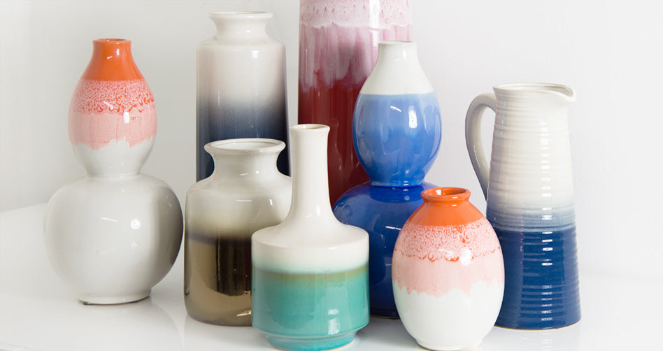 Eight shiny ceramic containers of various shapes, all two-tone white bleeding into a different, vibrant earth-tone color
