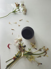 A vase of dead flowers, a single remaining stem