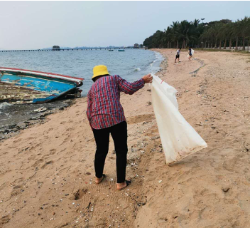 woman cleaning plastic from a beach