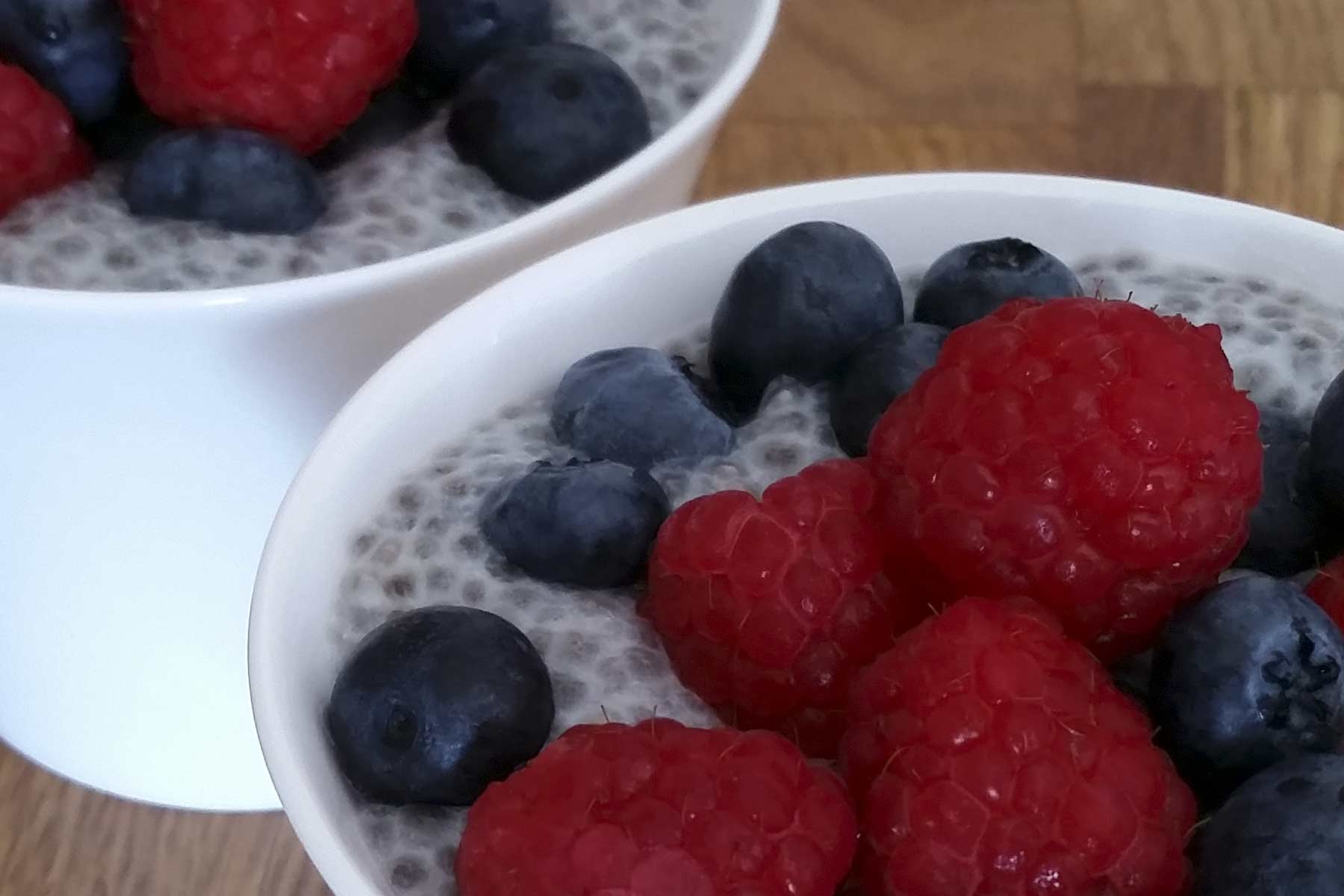 Chia seeds in almond milk topped with raspberries and blueberries | OneDTQ