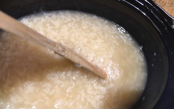 Place rice in a large mesh strainer over a large bowl and rinse several times until water runs clear. Add rice, water and chicken stock to a 6-quart slow cooker or crock pot and place on high setting for 5 hours, stirring occasionally with a wooden spoon, until soup thickens to consistency of a thick porridge. At this point the congee can be refrigerated and eaten later, or served immediately with pork, shiitake and bok choy added.