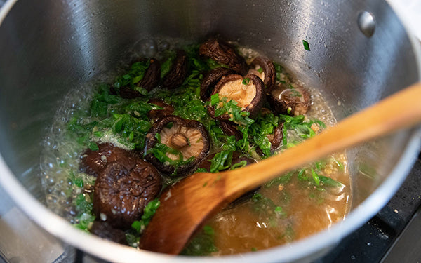 In a stockpot heat up the vegetable and sesame oils, and then add in the mushrooms and green onions. Sauté 3-4 minutes and then add in the garlic and ginger. Sauté an additional minute. 