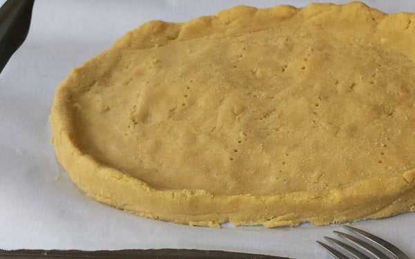 Place dough on a parchment lined cookie sheet and with your hands form an oval-rectangle crust with sides. With a fork, poke holes along the bottom of the crust. 