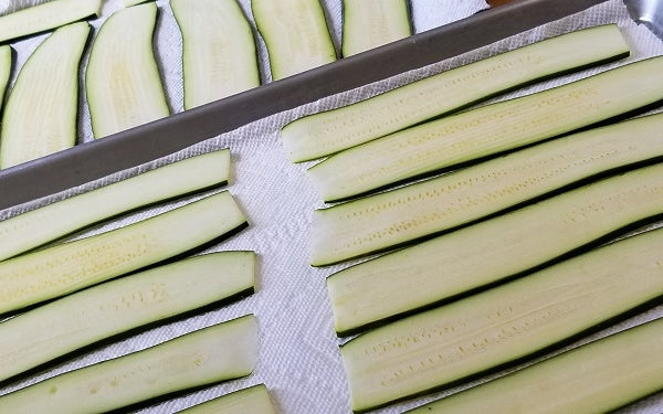 Line a baking sheet with paper towels. Sprinkle each side of zucchini slices with salt, lay them flat in a single layer onto the baking sheet, and let stand 15 minutes.