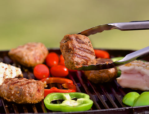 Photo of Grilled Chicken Being Picked Up with Green Bell Peppers in Background
