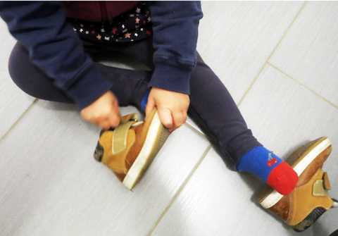 Child putting on shoe montessori method