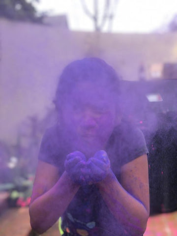 girl blowing purple dust