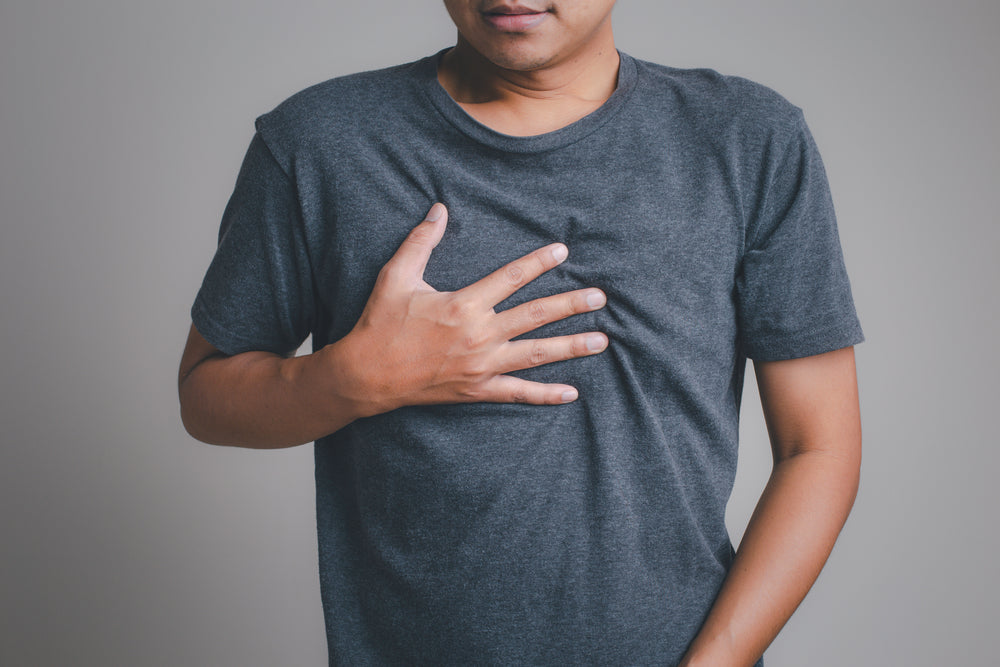 man holding chest from acid reflux pain