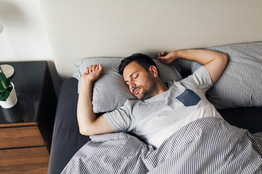 Man sleeps directly on his back with hands up near his head