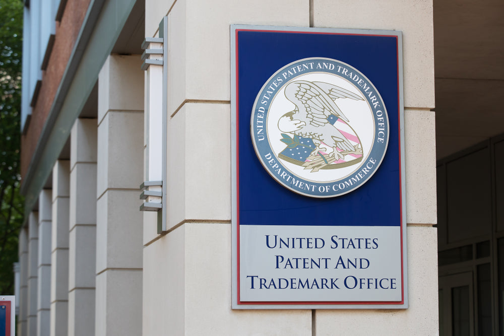 Photograph shows sign of United States Patent and Trademark Office outside of building
