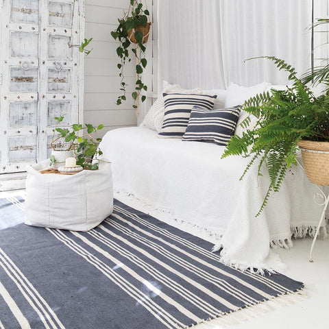white room with stripe rug and outdoor cushions in grey