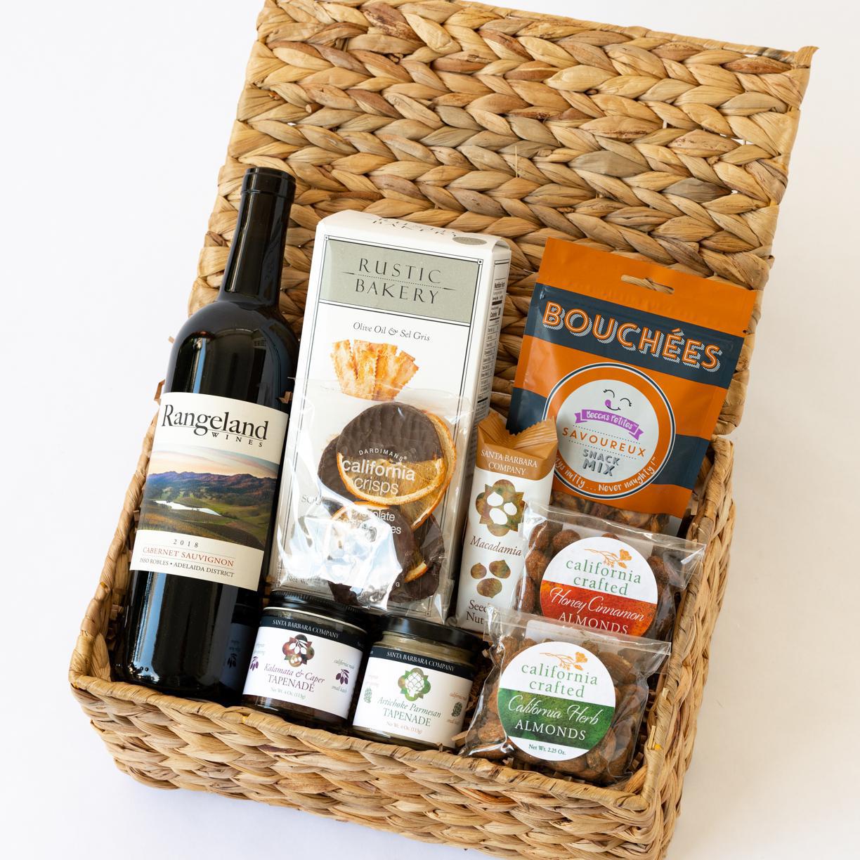 Gift basket filled with wine, sourdough botes, bouches, tapenade, almonds, chocolate dipped oranges and a macadamia bar