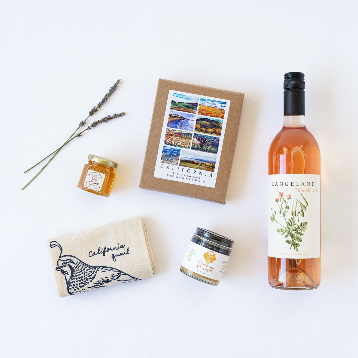 Wine, mini honey, mustard, box of cards, and birds towel on white background
