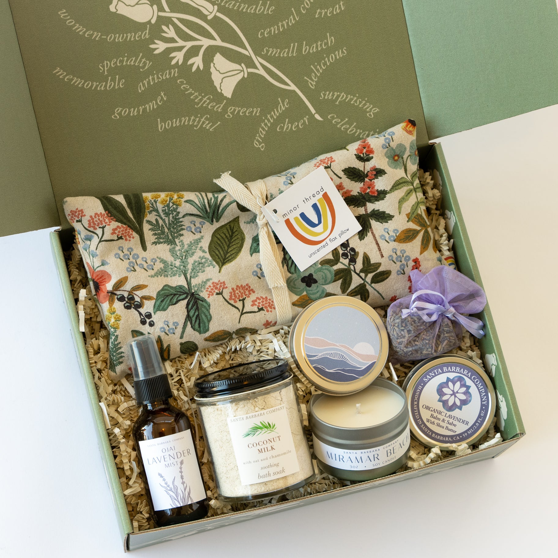 Green box with an eye pillow, apothecary products, and a candle