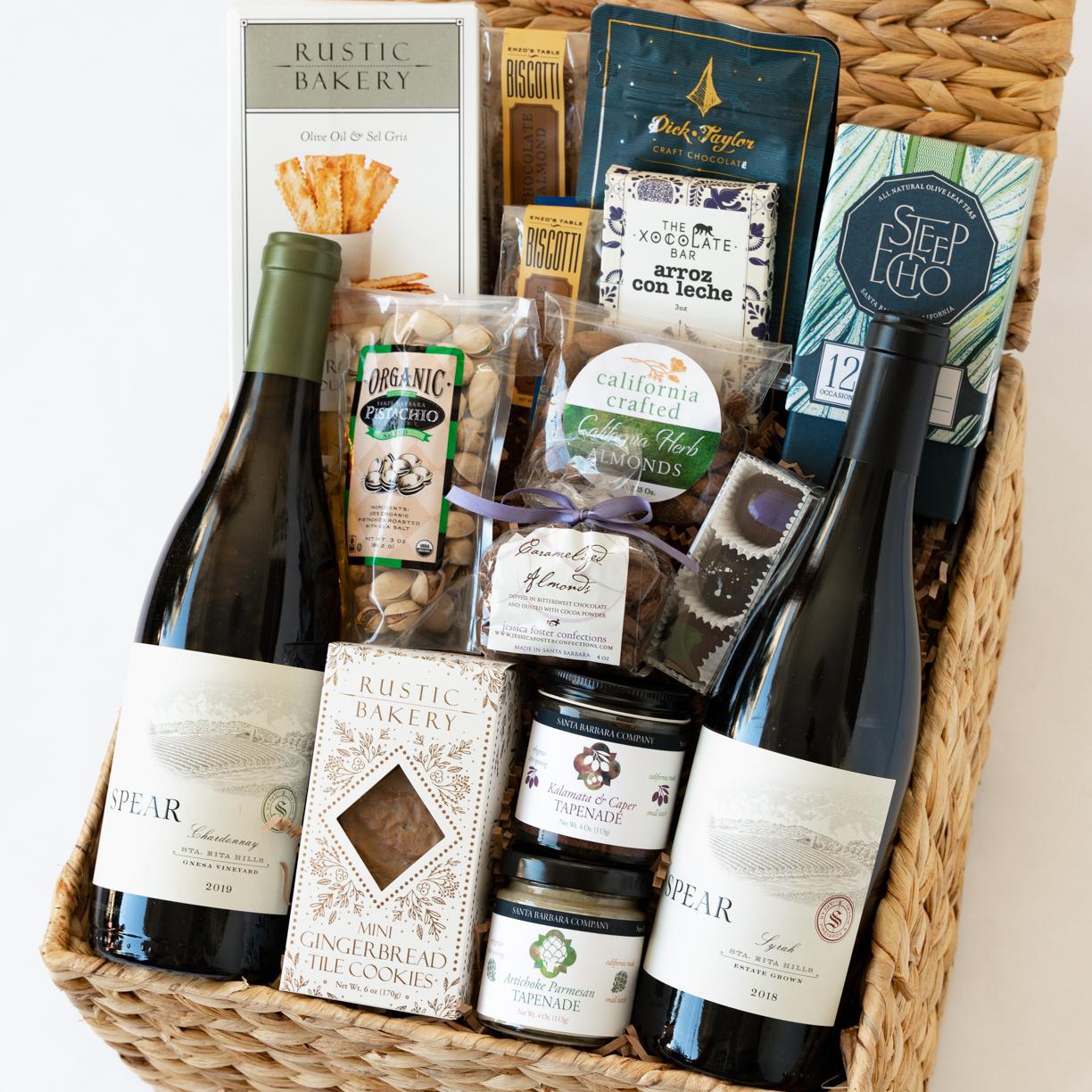 Basket filled with wine, tapenade, tea, caramels, almonds, chocolate, biscotti, pistachios, gingerbread, and sourdough bites