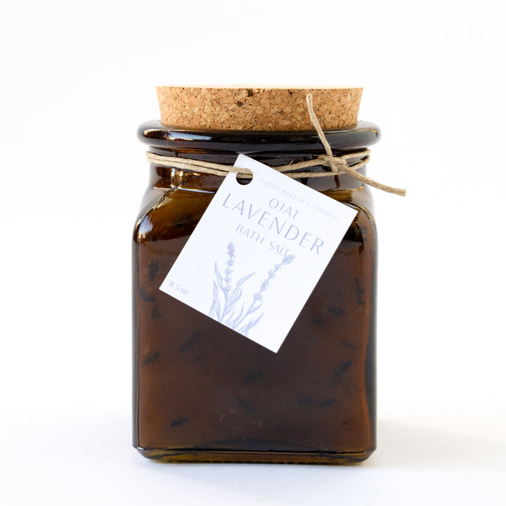 Glass amber jar with a cork plug with bath salts inside and a tag tied on with twine