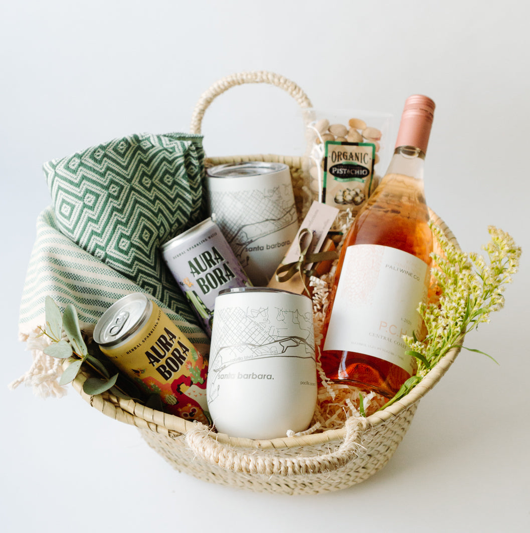 basket with wine, sparkling water, a blanket, wine tumblers, pistachios and truffles