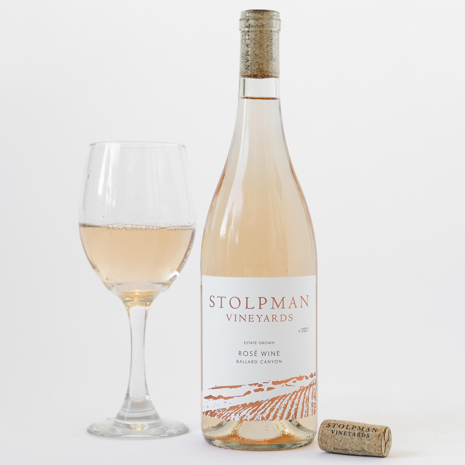 A bottle of Stolpman's estate Rosé next to a full wine glass on a white background