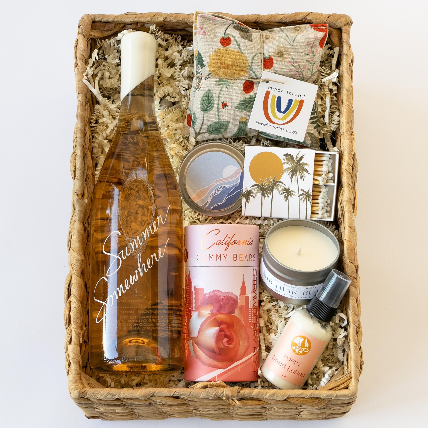 Summer somewhere gift basket with rosé, gummy bears, lotion, a candle, matched, and lavender sachets in a woven basket
