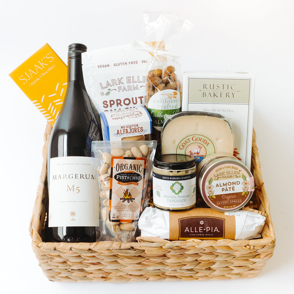Basket filled with wine, granola, almonds, sourdough bites, cheese, pistachios, salame, tapenade, and pate.