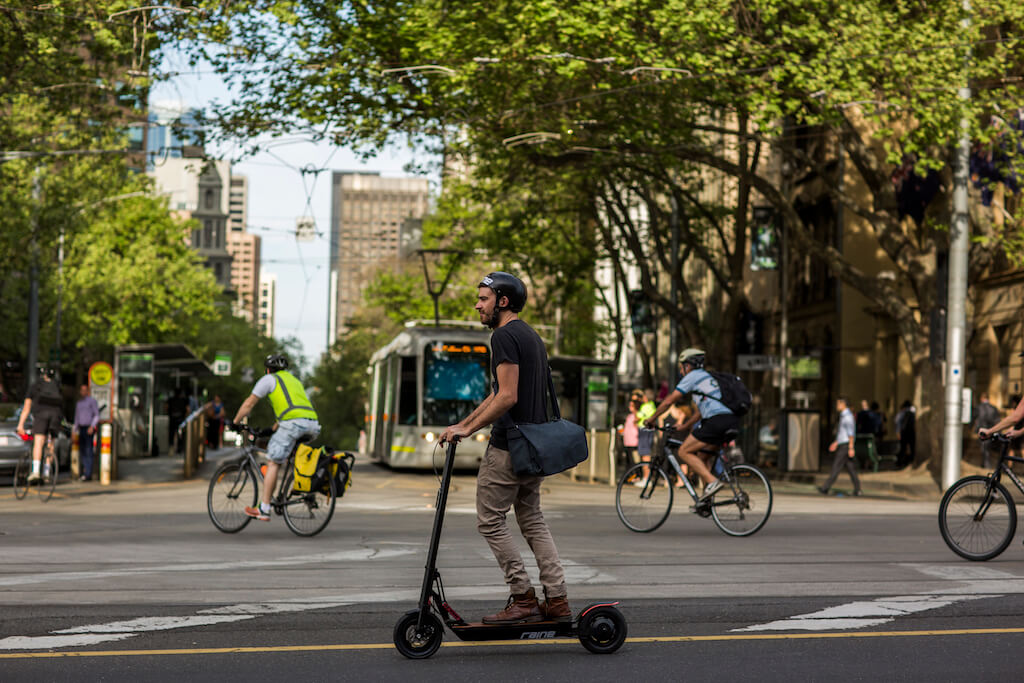 Man riding an electric scooter through a city wearing a helmet