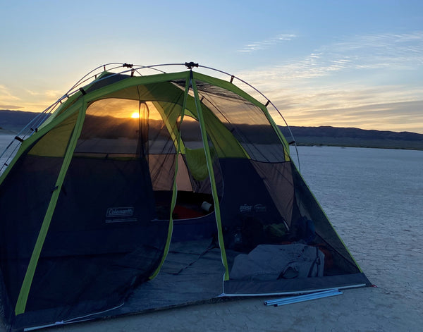 Sunrise through camping tent in wide open desert