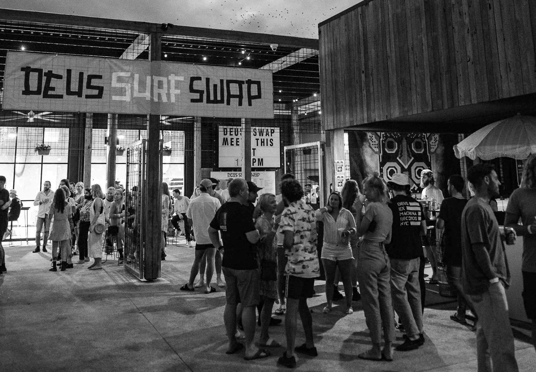 crowd under Deus surf swap sign