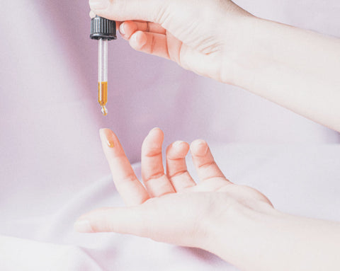 Pipette with golden coloured Akasha blends Facial oil above a finger