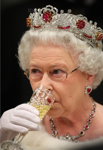 Queen Elizabeth wearing a diamond and ruby tiara while drinking Champagne