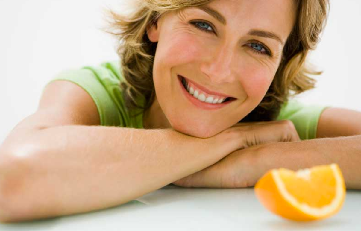 Woman smiling with Orange Vitamin C by hoodermatology.com