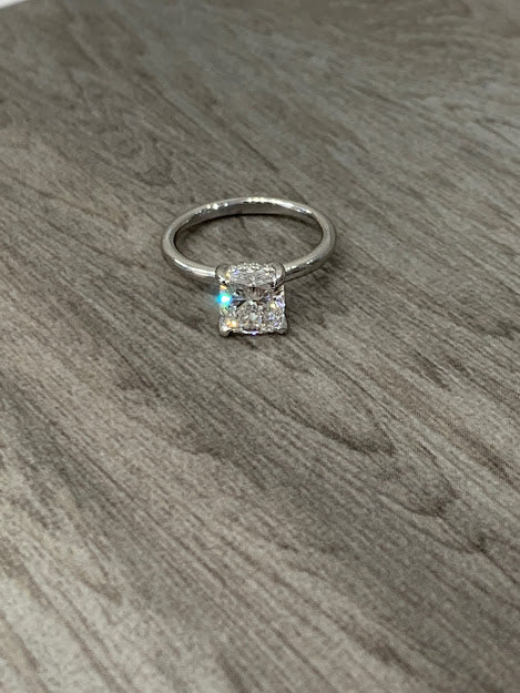 Cushion-Cut Center Stone with Diamond Hidden Halo Engagement Setting  This ring features a square cushion brilliant center stone set in an all-around comfort fit rounded solitaire shank with a diamond basket that elegantly cradles the center stone.